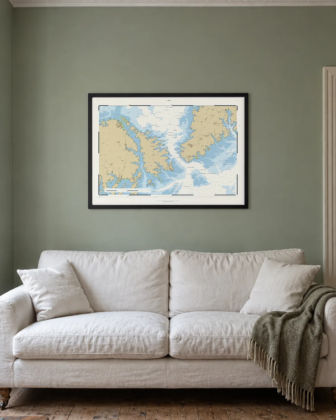 A Drowned Coast chart of Streatley, A1 in a black frame, hanging above a white sofa in an illustrated sitting room